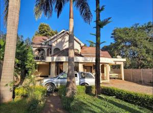 Un coche aparcado delante de una casa con palmeras. en Villa Jane in Arusha, en Arusha