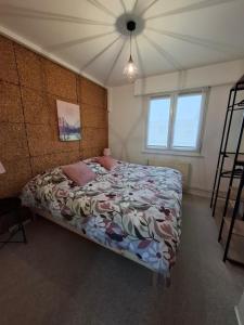 a bedroom with a bed with a floral comforter and two windows at Charmante maison familiale in Rixheim