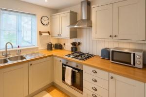 a kitchen with white cabinets and a sink and a microwave at Elegant 2BD Townhouse in Thirsk: Cozy & Stylish in Thirsk