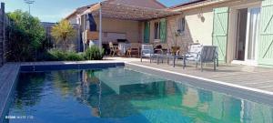 a swimming pool in a yard with chairs next to a house at Villa avec piscine - 3 chambres in Alignan-du-Vent
