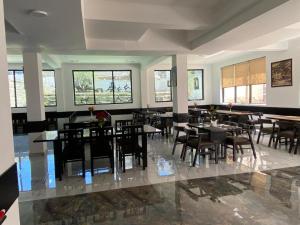 a dining room with tables and chairs and windows at Hotel Choskor in Leh