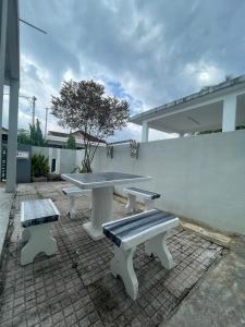 a picnic table and benches on a brick patio at D' Permata Homestay Kulim in Kulim