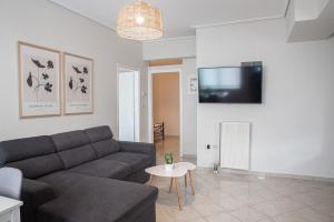 Una sala de estar con un sofá y un televisor en una pared. en Messinian Moon, en Kalamata