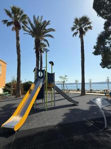 eine gelbe Rutsche auf einem Spielplatz mit Palmen in der Unterkunft Mili Minihouse in Kaštela