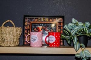 dos tazas de café sentadas en un estante con una cesta en La Casa, en Prijedor