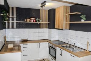 Una cocina con gabinetes blancos y un fregadero. en La Casa, en Prijedor