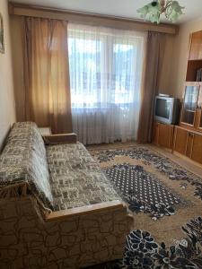 ein Schlafzimmer mit einem Bett und einem Fenster und einem Fernseher in der Unterkunft Gorodok Home in Skole