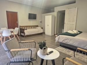 a room with two beds and a table and chairs at Archers Guest House in Patentie