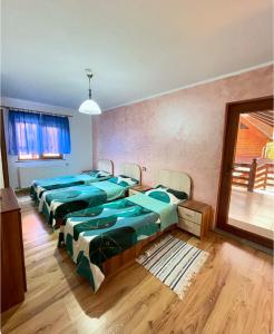 a group of four beds in a room at Casa de vacanța Ariana in Borşa