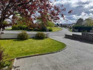 an empty street with a tree and a driveway at Home in Ballina, Ireland in Ballina