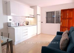 ein Wohnzimmer mit einer blauen Couch und einer Küche in der Unterkunft La Caleta Holiday Homes in Castillo del Romeral + 27 Fotos