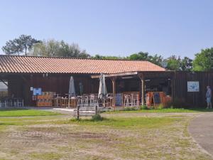 AzurLandes Azur mobil home 38 m2 7km de vieux boucau的一座有桌椅和遮阳伞的建筑