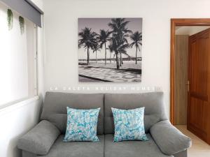ein Sofa im Wohnzimmer mit einem Bild von Palmen in der Unterkunft La Caleta Holiday Homes in Castillo del Romeral