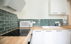 a kitchen with white cabinets and green tile on the wall at Le Gare Nord T3 de Haut Standing Cosy et Relaxant in Nantes