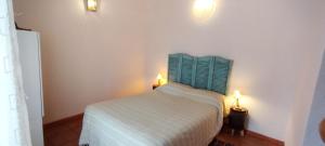 a bedroom with a bed with a green headboard and two lights at Casa da Bica in Alvalade