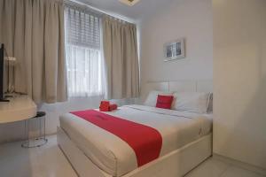 una camera da letto con un letto grande con una coperta rossa di RedDoorz Plus near Parahyangan University a Bandung