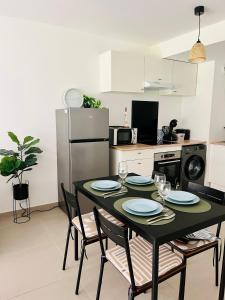 Una cocina con una mesa negra con sillas y una cocina con refrigerador. en Appartement 2 pièces Résidence avec Piscine, en Villeneuve-Loubet