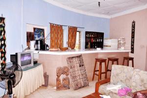 Ein Wohnzimmer mit Fernseher, einigen Stühlen und einer Theke. in der Unterkunft Hôtel Bellevue in Natitingou