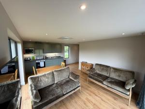 a living room with two couches and a kitchen at Threipmuir Lodge in Loanhead