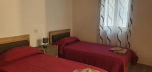 a bedroom with two beds with red sheets and a window at KIAN Apartment in Victoria
