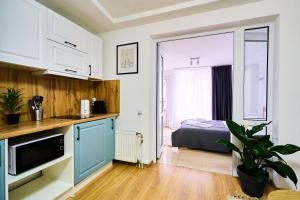 a kitchen with blue cabinets and a bed in a room at Chisinau Airport Zone Studio Cozy & Connected in Chişinău