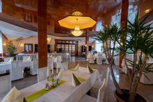 a restaurant with white tables and white chairs and plants at Kraichtaler Hof in Kraichtal