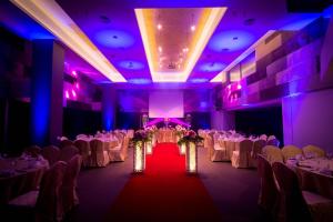 a banquet hall with white tables and chairs and purple lighting at Mandurah Hotel in Kuantan