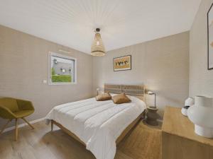 a bedroom with a large bed and a chair at Maison neuve avec terrasse et jardin pour 6 in Beg-Meil