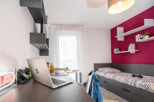 a bedroom with a desk with a laptop on it at Résidence Nemea Clermont Centre in Clermont-Ferrand
