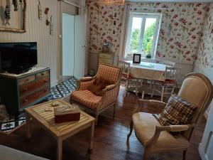 a living room with chairs and a television and a table at O'TY'ZOISEAUX - Plus proche de la nature - Meublé tourisme classé 4 étoiles in Scaër