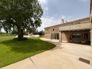a stone house with a tree and a patio at Casa Rural Mas Homs in Parets de Dalt