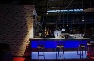 a bar with four blue stools in a room at Belle maison conviviale in Coulommiers