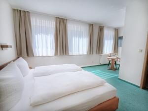two beds in a hotel room with windows at REGIOHOTEL Bunte Stadt in Wernigerode
