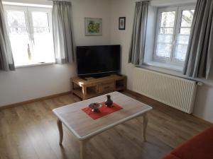 Una sala de estar con televisión y una mesa de café. en Ferienwohnung Beim Schuster, en Hitzleried