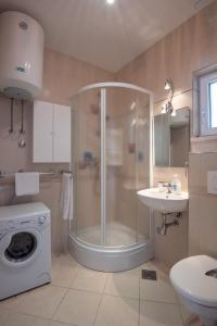 a bathroom with a shower and a sink and a washing machine at APARTMENTS BRUNO 1&2 - two-room penthouse apartments - wonderful panoramic view of the sea - the best location, first row to the beach - 10 minutes from Supetar ferry port - free secured parking - facilities nearby in Sutivan +37 photos