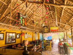 a restaurant with wooden ceilings and tables and chairs at COCCOBELLO AFRICAN Village- in Nungwi