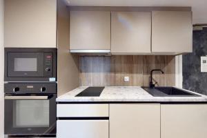 cocina con armarios blancos y microondas negro en Canvas Manchester, en Mánchester