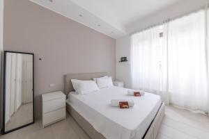 a white bedroom with a large bed and a mirror at Via Santa Croce 1 in Milan