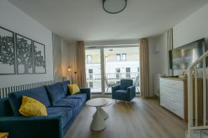 a living room with a blue couch and a table at Florina Apartamenty dwupoziomowe in Łeba