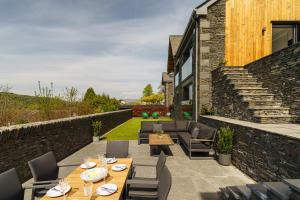 a patio with tables and chairs and a stone wall at Midways, Stunning Retreat in the Heart of Bowness in Bowness-on-Windermere