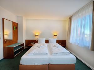 a bedroom with a large white bed with a window at REGIOHOTEL Bunte Stadt Wernigerode in Wernigerode