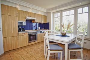 a kitchen with wooden cabinets and a white table and chairs at Ferienwohnung mit traumhaftem Meerblick - Haus am Meer FeWo 05 in Lohme