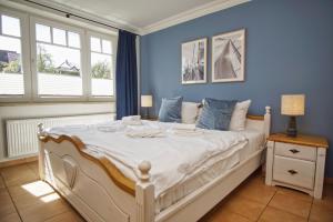 a bedroom with a white bed with blue walls and windows at Ferienwohnung mit traumhaftem Meerblick - Haus am Meer FeWo 05 in Lohme