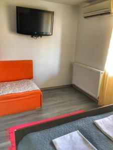 mały pokój z pomarańczowym łóżkiem i telewizorem z płaskim ekranem w obiekcie Jázmin Apartmanok w mieście Mórahalom +2 zdjęcia