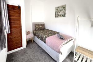 a small bedroom with a bed with a pink blanket at PLEASANT View Impressive Home In Stunning Rhondda Valley By Staystaycations in Pontypridd