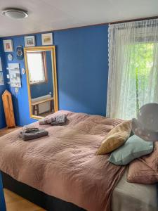 a bedroom with a large bed with a blue wall at Boshuisjes Veluwe Lila met omheinde tuin in Putten +15 photos