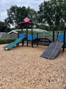 a playground with a slide and an umbrella at Boshuisjes Veluwe Lila met omheinde tuin in Putten