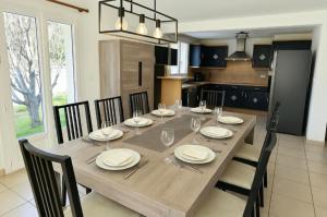 a wooden table with chairs and plates and wine glasses at Maison Familiale & Confortable proche Plage in Luc-sur-Mer
