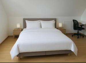 a bedroom with a large white bed and a chair at Maison Familiale & Confortable proche Plage in Luc-sur-Mer