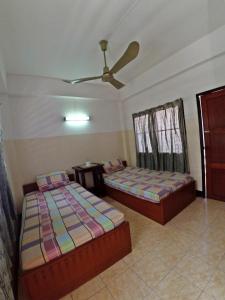 a bedroom with two beds and a ceiling fan at Sarah Guest House in Chiang Mai